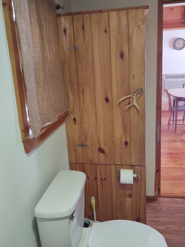 bathroom featuring hardwood / wood-style floors, toilet, and an AC wall unit