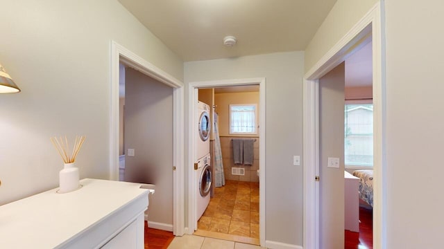 hall featuring stacked washer / drying machine and light tile patterned flooring