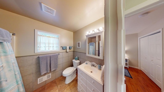 bathroom featuring vanity, toilet, and tile walls