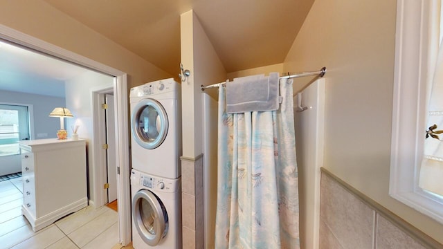 laundry room with stacked washer / dryer and light tile patterned floors