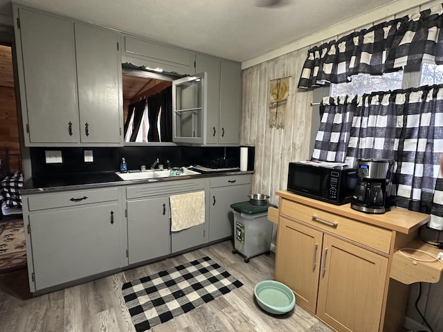 kitchen featuring hardwood / wood-style floors, wood counters, wood walls, sink, and decorative backsplash