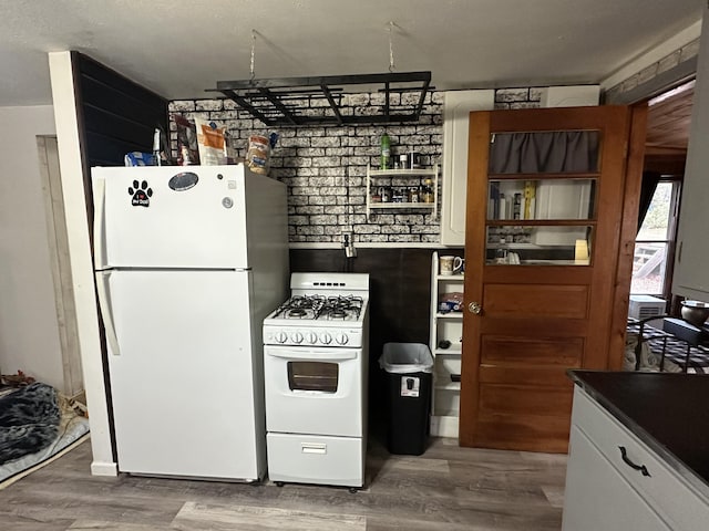 kitchen featuring white cabinets, white appliances, and hardwood / wood-style flooring