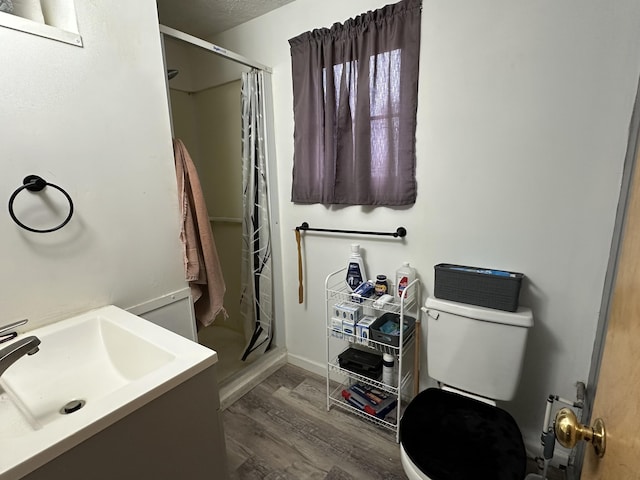 bathroom with vanity, hardwood / wood-style flooring, toilet, walk in shower, and a textured ceiling