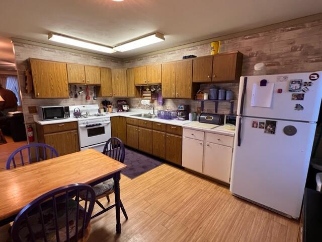 kitchen featuring white appliances, wooden walls, and sink