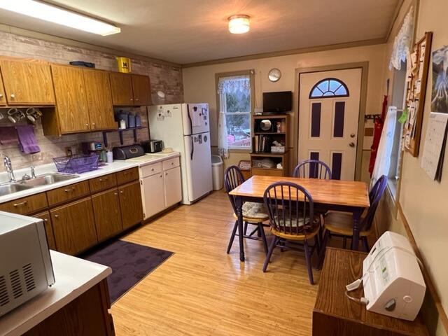 kitchen with sink, backsplash, white fridge, light hardwood / wood-style floors, and ornamental molding