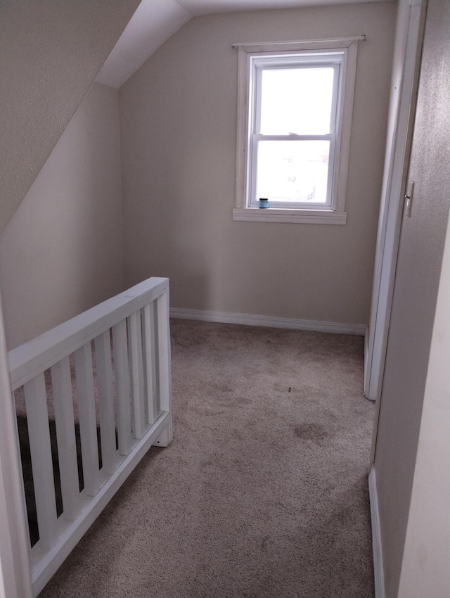 additional living space featuring light colored carpet and vaulted ceiling