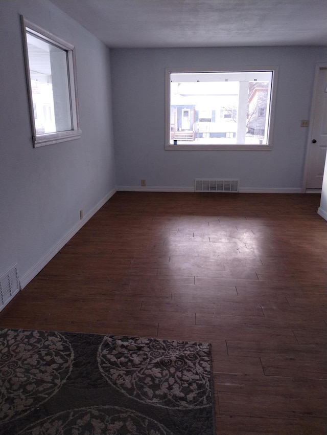 unfurnished room with dark hardwood / wood-style floors and a healthy amount of sunlight