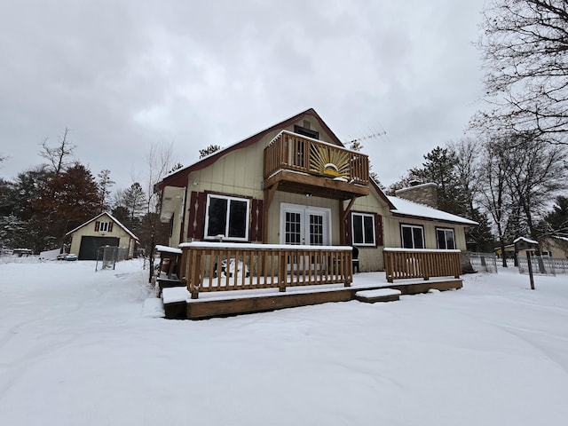 view of front of house with a balcony, an outdoor structure, and french doors