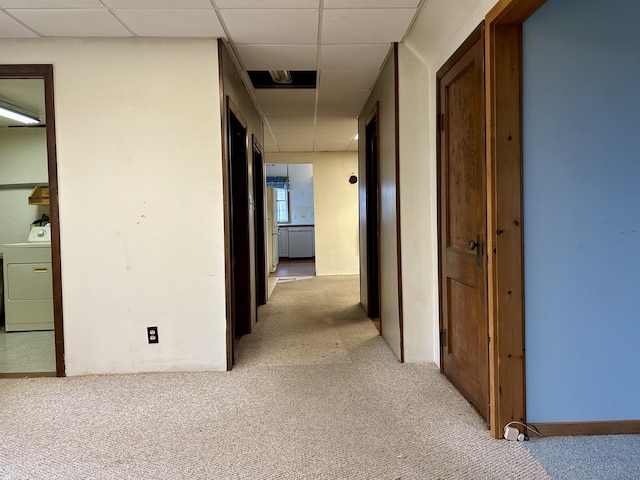 corridor with washer / clothes dryer and light colored carpet