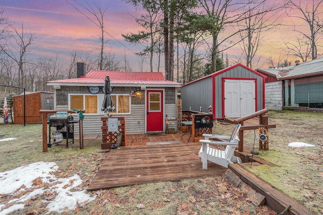 back house at dusk featuring a deck and a storage shed