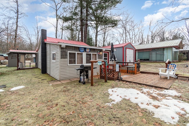 rear view of house featuring a lawn, a wooden deck, and a storage shed