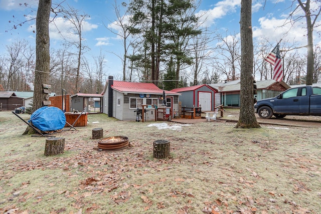 back of property with a fire pit and a storage unit