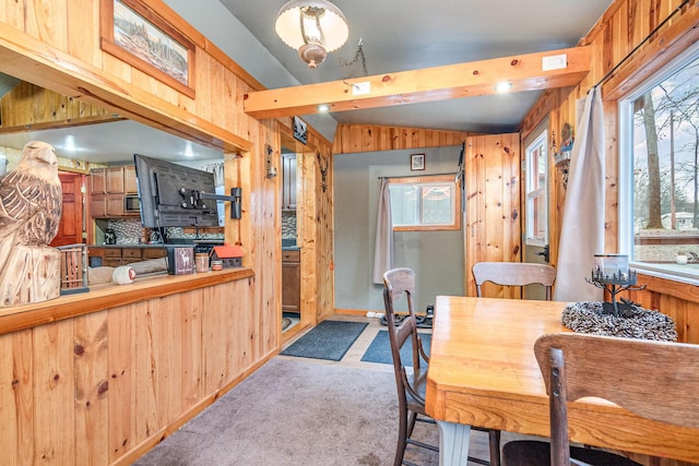 carpeted dining room featuring wooden walls