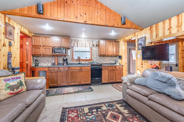 kitchen featuring lofted ceiling, sink, light tile patterned floors, black dishwasher, and built in microwave