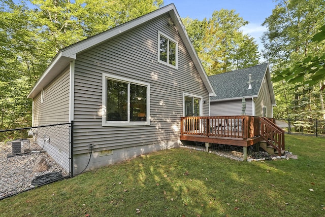 rear view of house featuring central AC, a deck, and a lawn