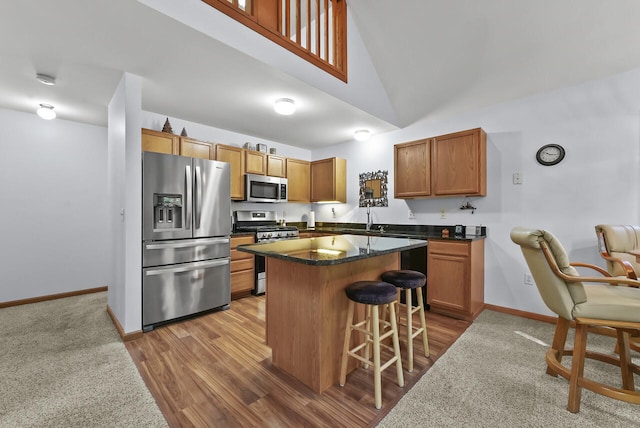 kitchen with stainless steel appliances, high vaulted ceiling, dark stone countertops, wood-type flooring, and a breakfast bar area