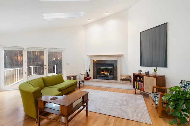 living room featuring lofted ceiling with skylight and light hardwood / wood-style floors