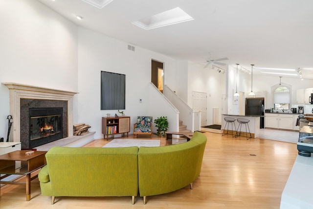 living room featuring ceiling fan, a fireplace, light hardwood / wood-style floors, and vaulted ceiling