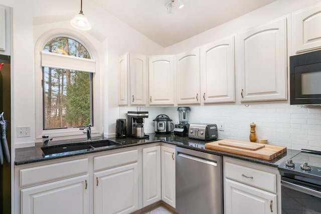 kitchen with sink, hanging light fixtures, dark stone countertops, white cabinets, and appliances with stainless steel finishes