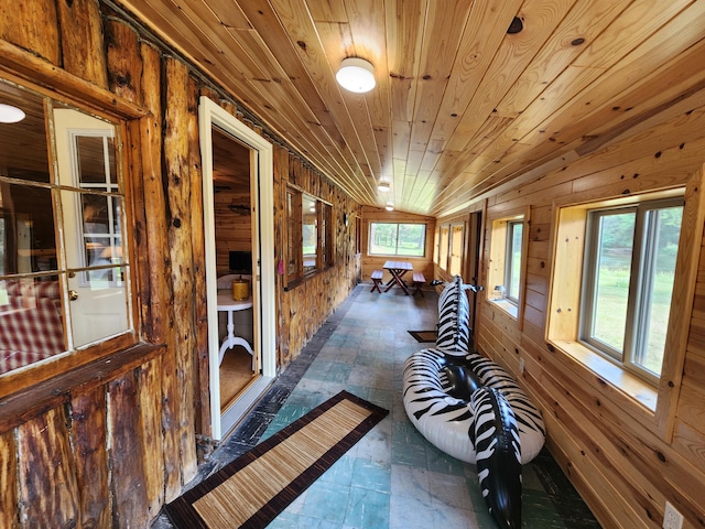 hall featuring lofted ceiling, wooden walls, and wooden ceiling