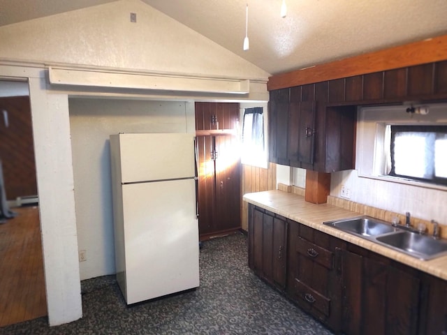 kitchen featuring lofted ceiling, sink, wooden walls, dark brown cabinets, and white fridge