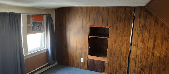 unfurnished bedroom with a textured ceiling and wood walls