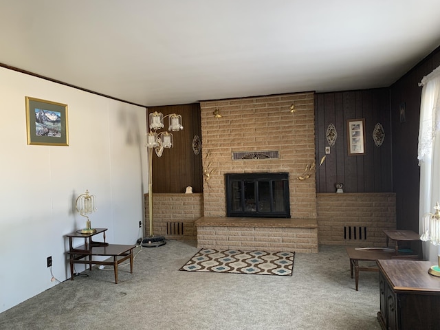 living room with carpet, a brick fireplace, and wooden walls