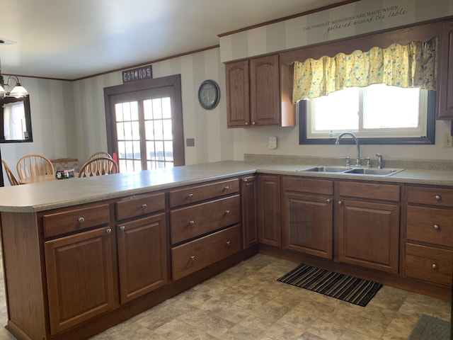 kitchen with decorative light fixtures, light countertops, a sink, and a peninsula