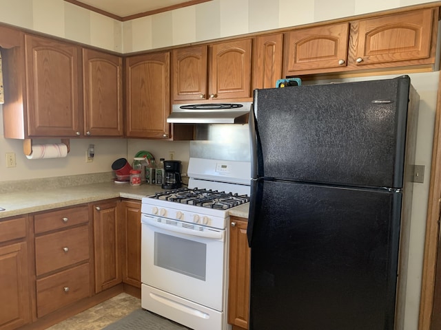 kitchen with brown cabinets, white gas range, light countertops, freestanding refrigerator, and under cabinet range hood