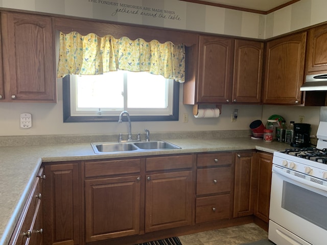 kitchen with light countertops, a sink, under cabinet range hood, and white gas range oven