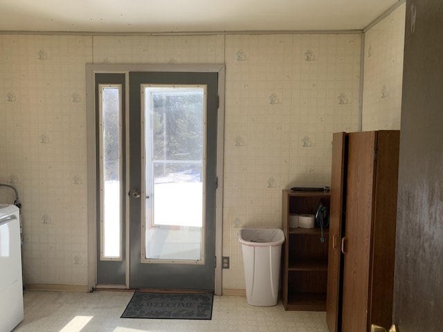 doorway to outside featuring baseboards, light floors, washer / clothes dryer, and wallpapered walls