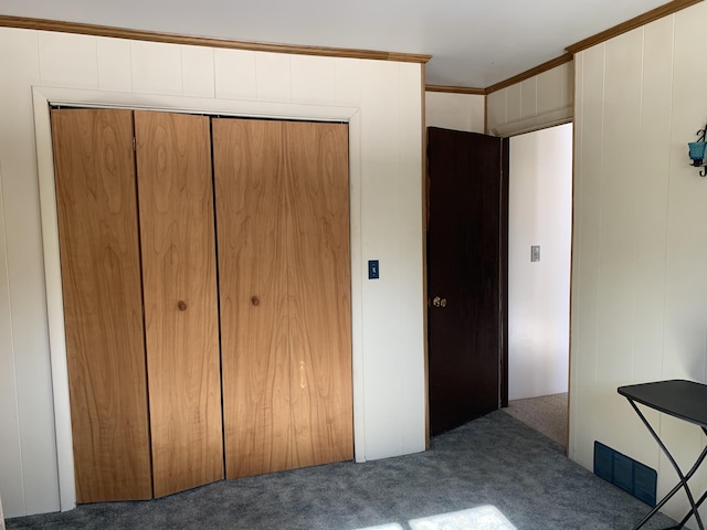 unfurnished bedroom with ornamental molding, a closet, carpet, and visible vents