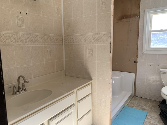 bathroom featuring tile patterned flooring, tile walls, toilet, and vanity