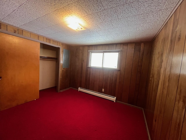 unfurnished bedroom with wooden walls, a closet, and a baseboard heating unit