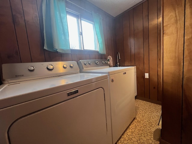 washroom with washer and dryer, wood walls, and a textured ceiling