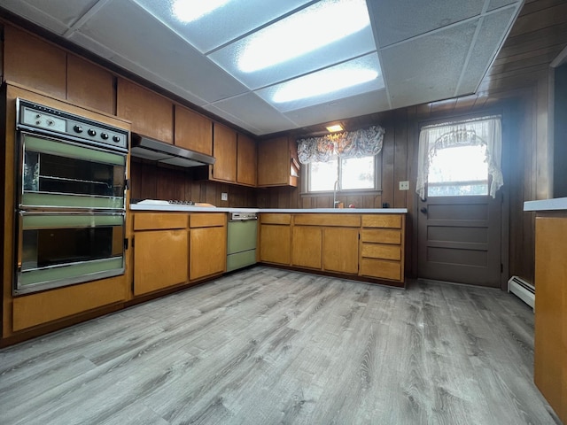 kitchen featuring a drop ceiling, ventilation hood, sink, black double oven, and a baseboard radiator