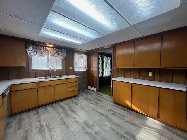 kitchen featuring a drop ceiling, wood walls, sink, light wood-type flooring, and baseboard heating