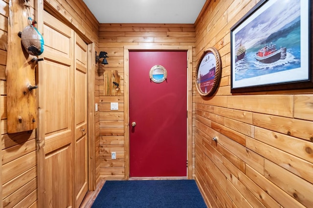 doorway with carpet and wood walls