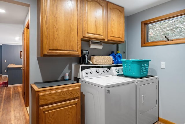 laundry room with cabinets, light hardwood / wood-style floors, and washing machine and clothes dryer