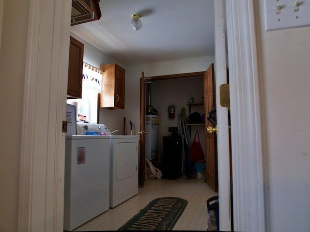 clothes washing area featuring strapped water heater and washer and clothes dryer