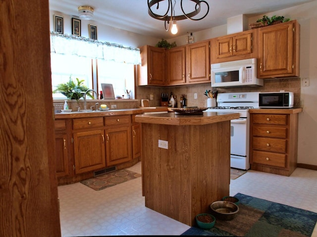 kitchen with white appliances, tasteful backsplash, a kitchen island, and sink