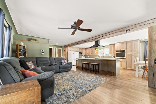 living room with ceiling fan, sink, and light wood-type flooring