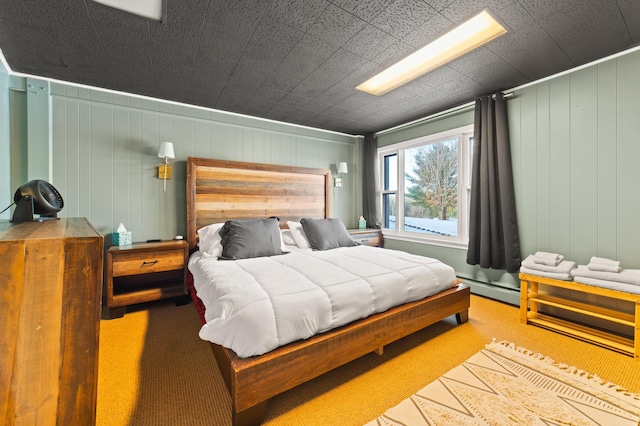 bedroom featuring baseboard heating, wooden walls, and carpet floors