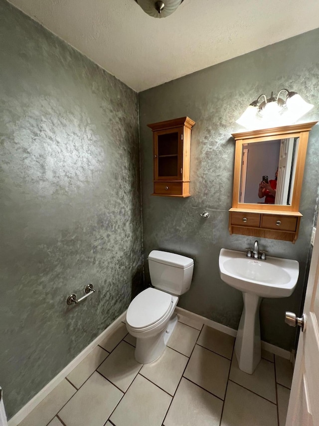 bathroom with tile patterned flooring, a textured ceiling, toilet, and sink