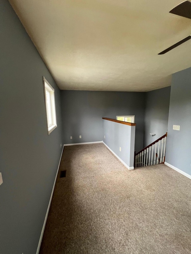 unfurnished room with ceiling fan and carpet