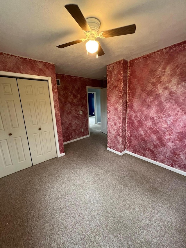 unfurnished bedroom featuring ceiling fan, a closet, dark carpet, and a textured ceiling