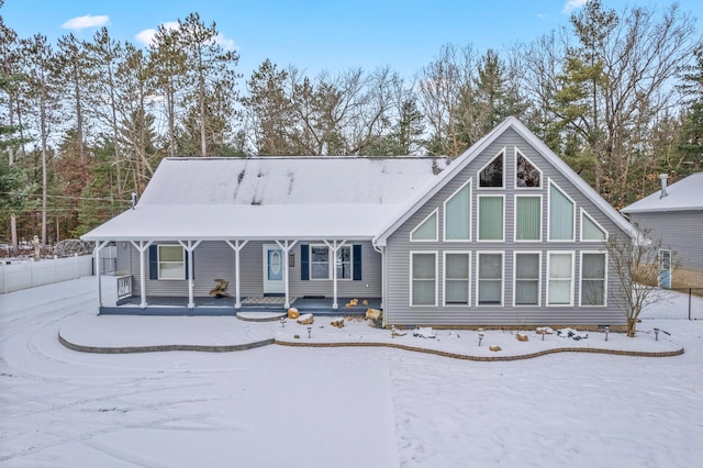 snow covered rear of property featuring covered porch