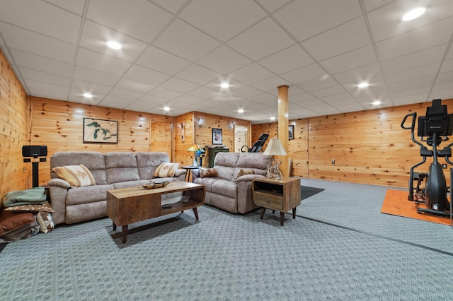 living room featuring a drop ceiling, carpet floors, and wood walls