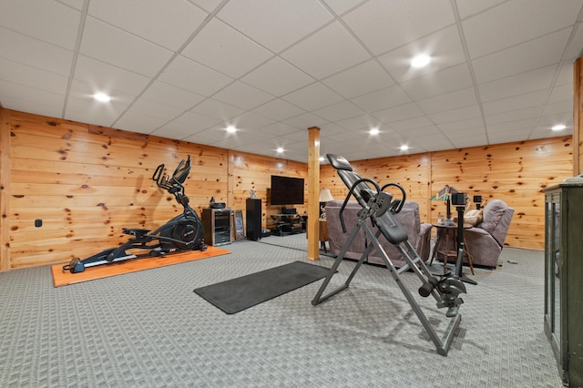 workout area featuring a drop ceiling, wood walls, and carpet