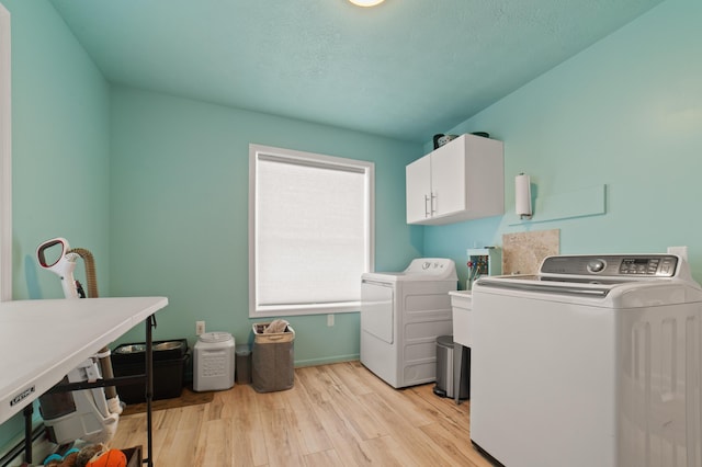 clothes washing area with cabinet space, light wood-style flooring, and independent washer and dryer